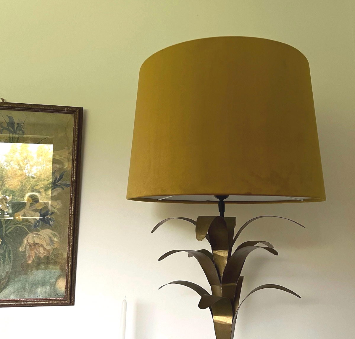A mustard velvet french drum lampshade on a metallic brushed brass palm leaf table lamp base