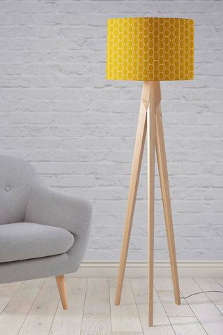 Mustard yellow table lamp with a white geometric design on a vibrant lampshade and wooden tripod legs