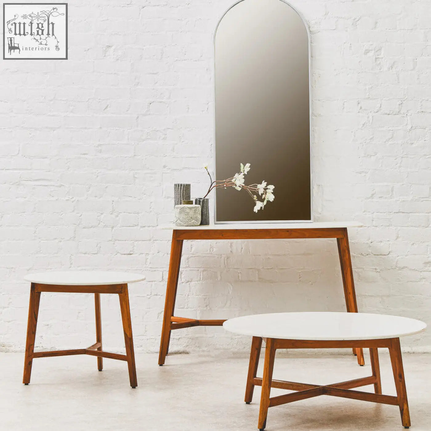 Arched mirror with sleek minimalist frame reflects white marble round side table made of acacia wood