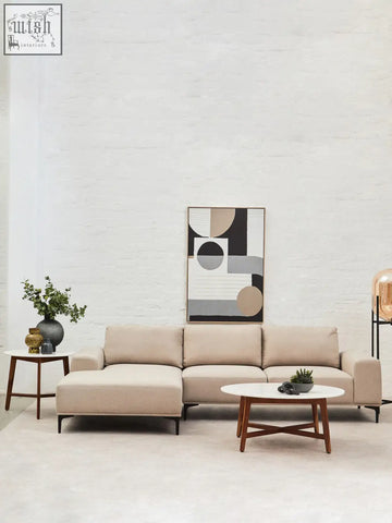 Beige sectional sofa with clean lines and low-profile wooden legs next to a white marble round side table with acacia wood base