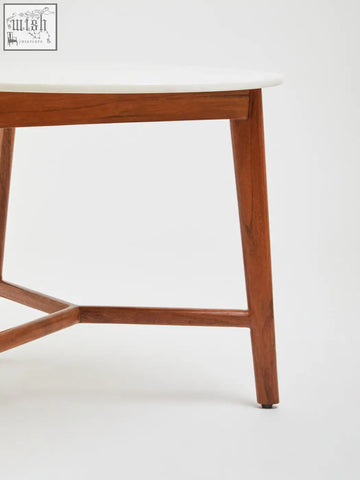 A mid-century modern white marble round side table with warm acacia wood legs and a smooth marble top