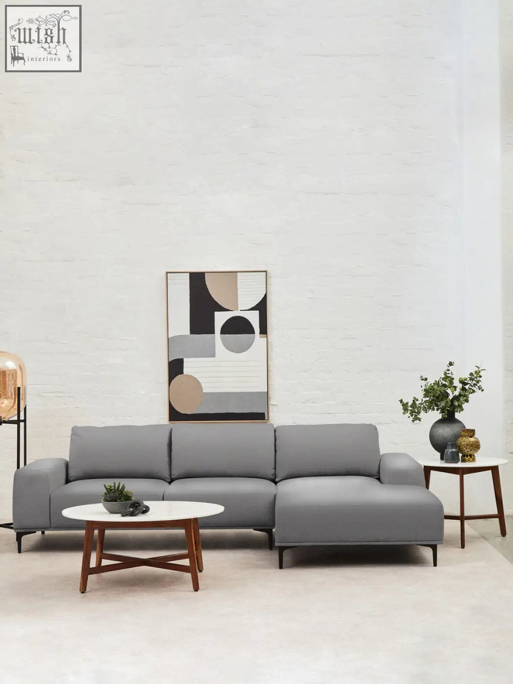 Modern gray sectional sofa with chaise lounge next to myan acacia wood and white marble round side table
