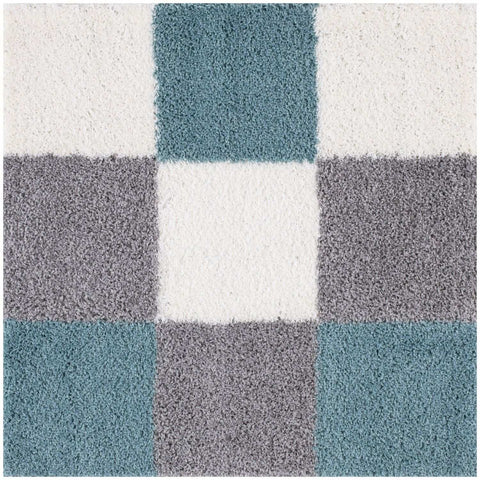 A plush shaggy area rug with a geometric pattern of duck egg blue and gray squares on a white background