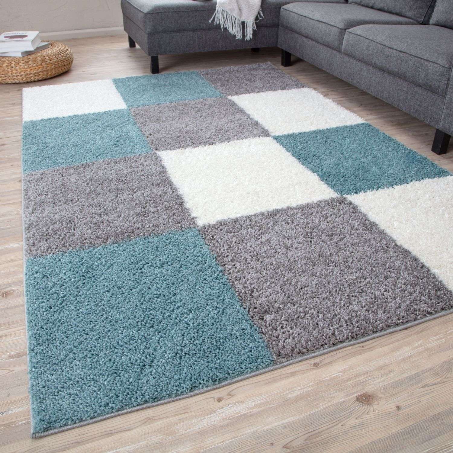 A plush shaggy area rug with a geometric patchwork design in duck egg blue gray and cream colors