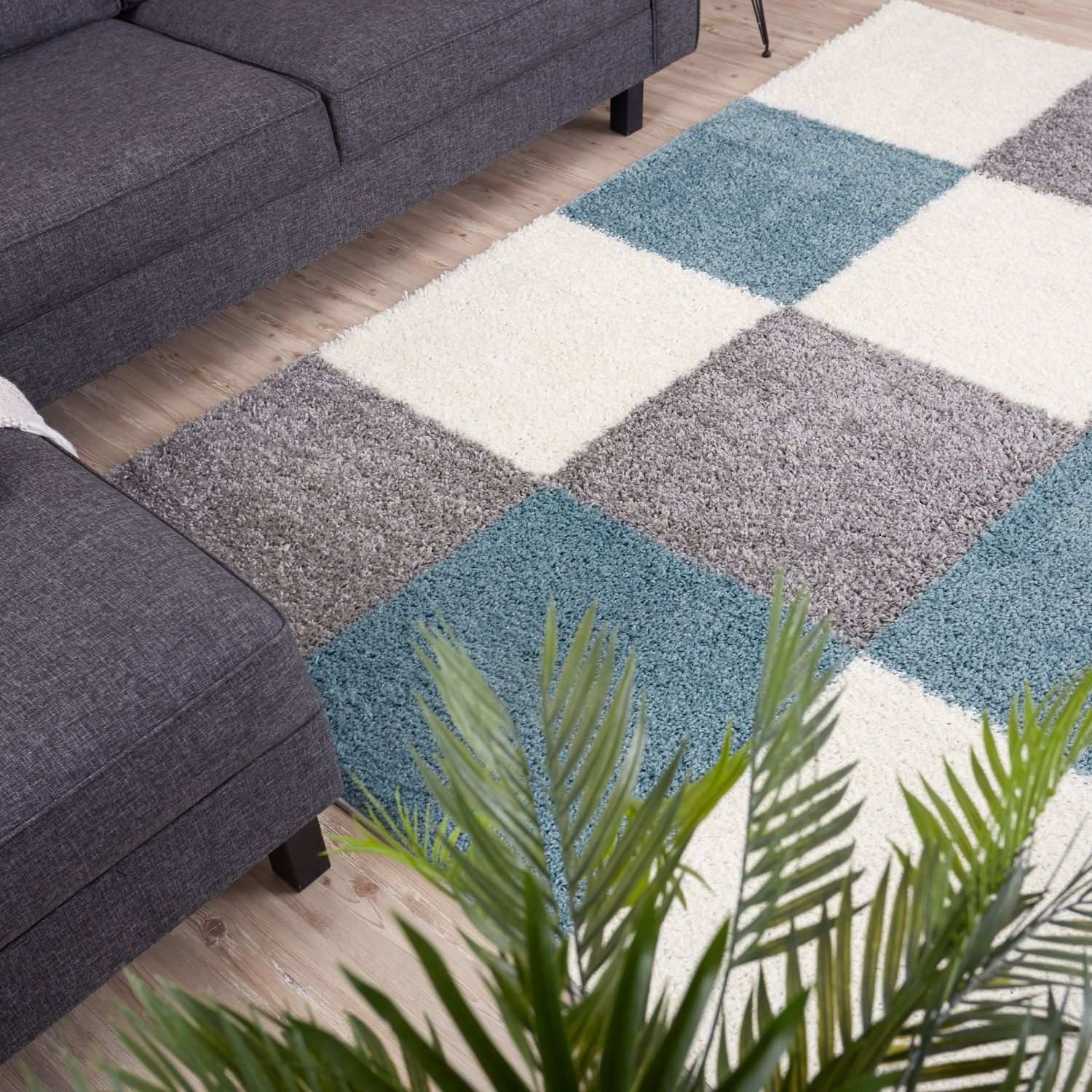 A plush shaggy area rug with a geometric pattern in duck egg blue gray and cream square patches