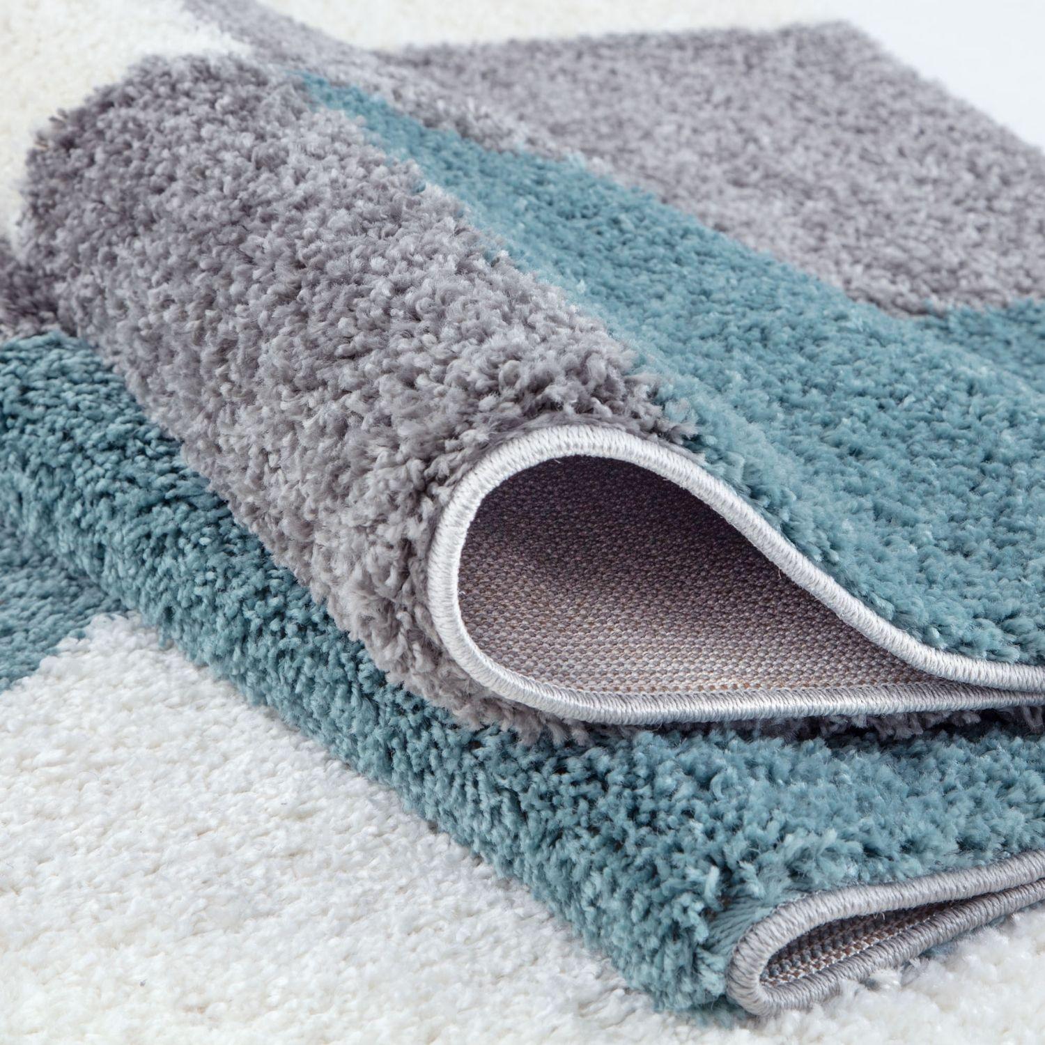 A plush two toned bath mat in soft gray and duck egg blue with shaggy texture and neatly stitched edges