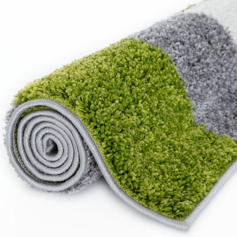 A plush myshaggy geometric green bath mat rolled up in vibrant green and soft gray colors