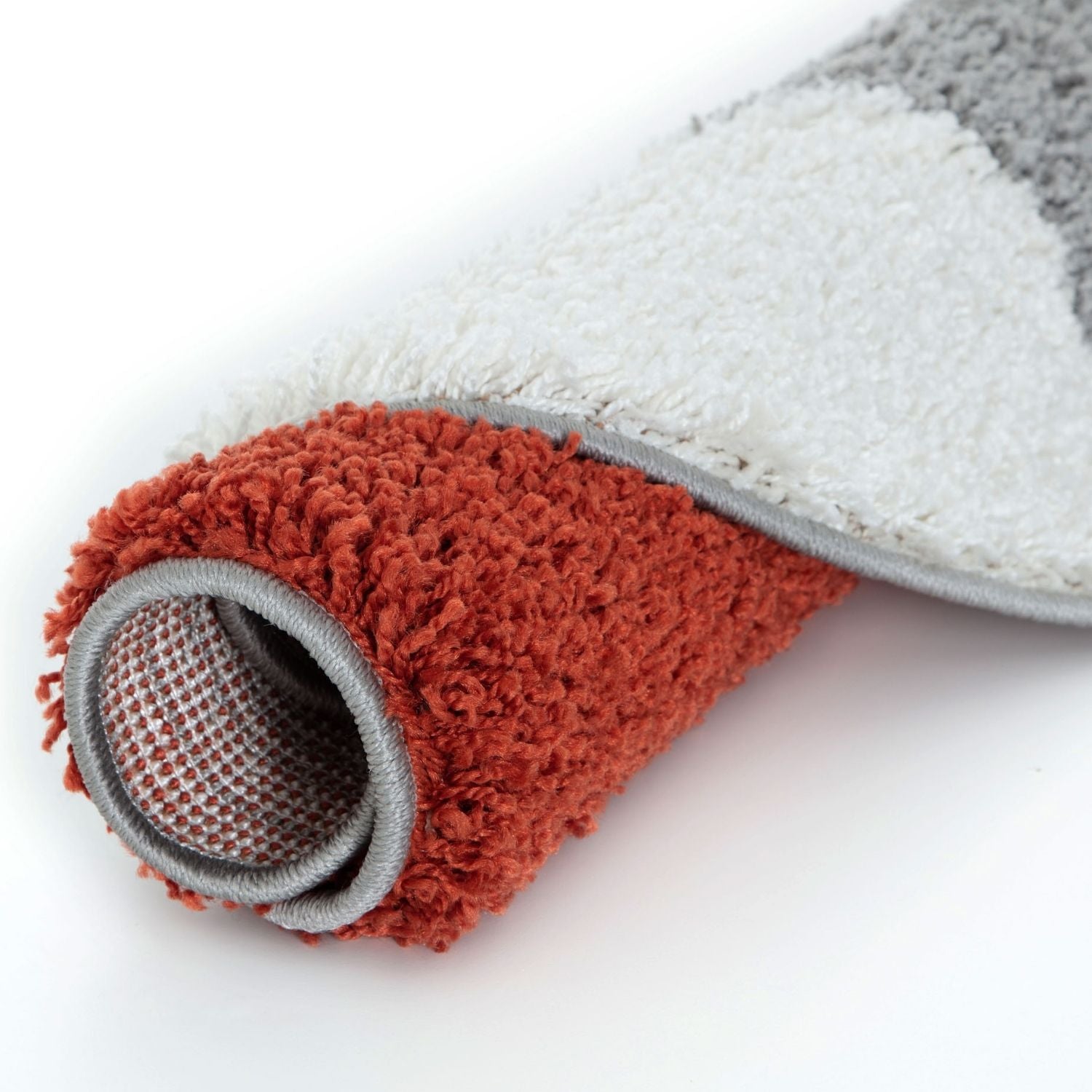 A plush rolled-up myshaggy geometric terra rug with a terracotta fuzzy surface and gray border trim