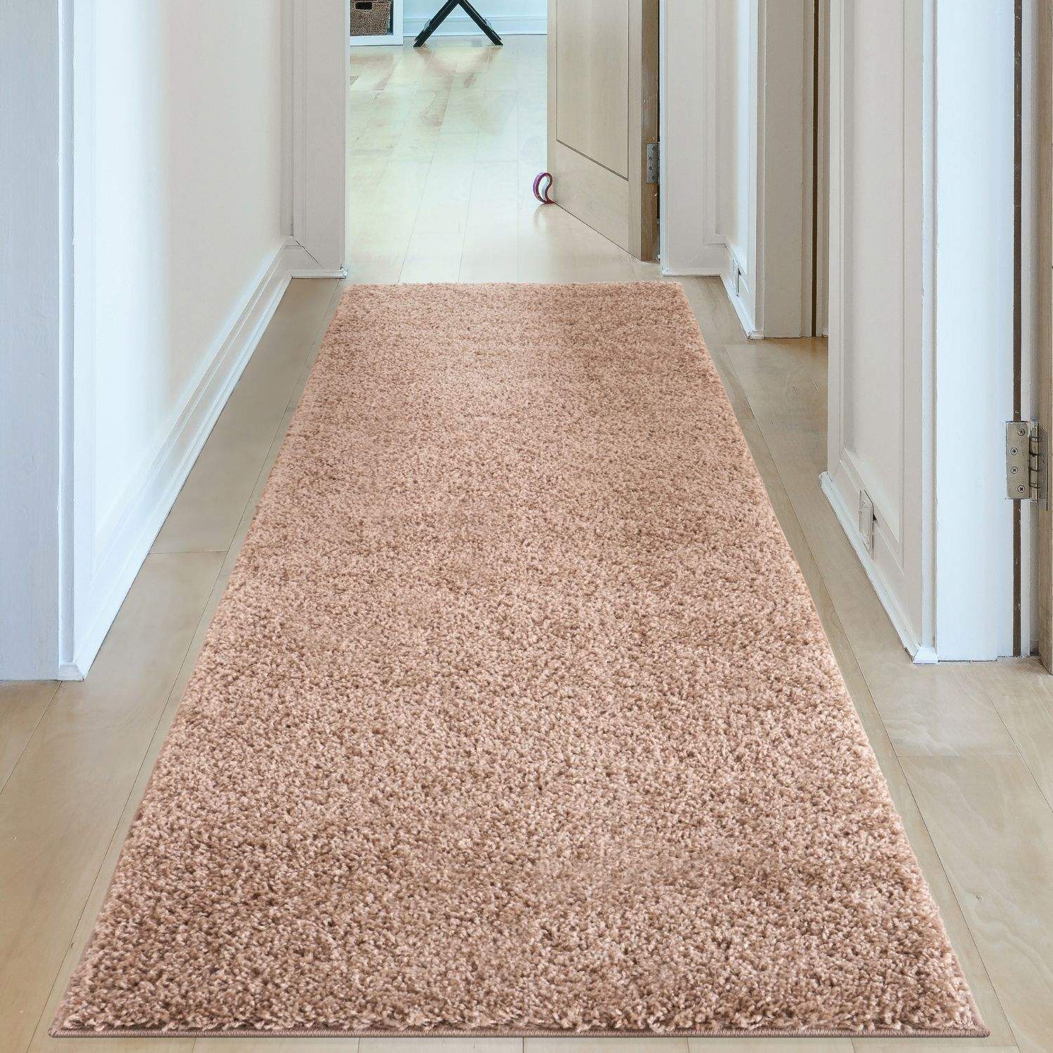 A plush light pink shaggy runner rug along a hallway floor featuring myshaggy solid beige rug style