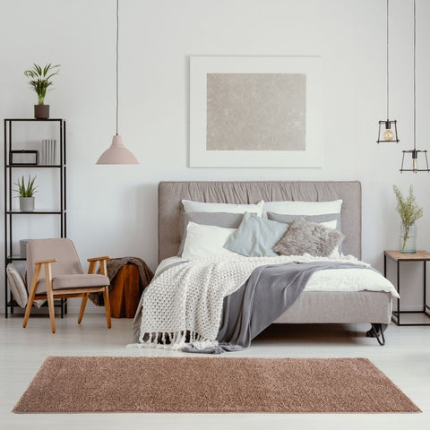 A plush solid beige rug myshaggy solid beige with soft shaggy texture lying in front of the bed