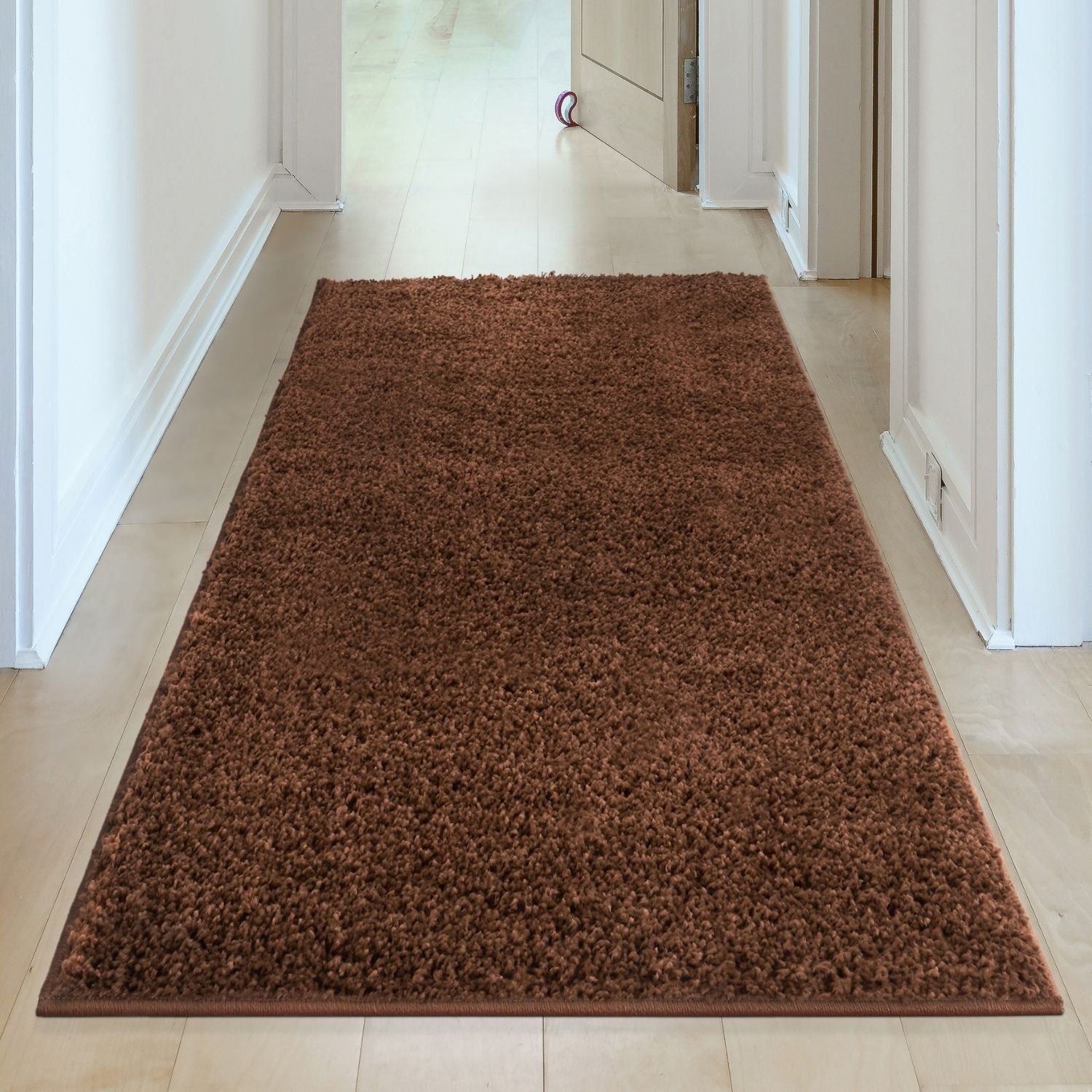 A plush myshaggy solid brown rug with soft shaggy texture lies centered in the hallway as a brown rug