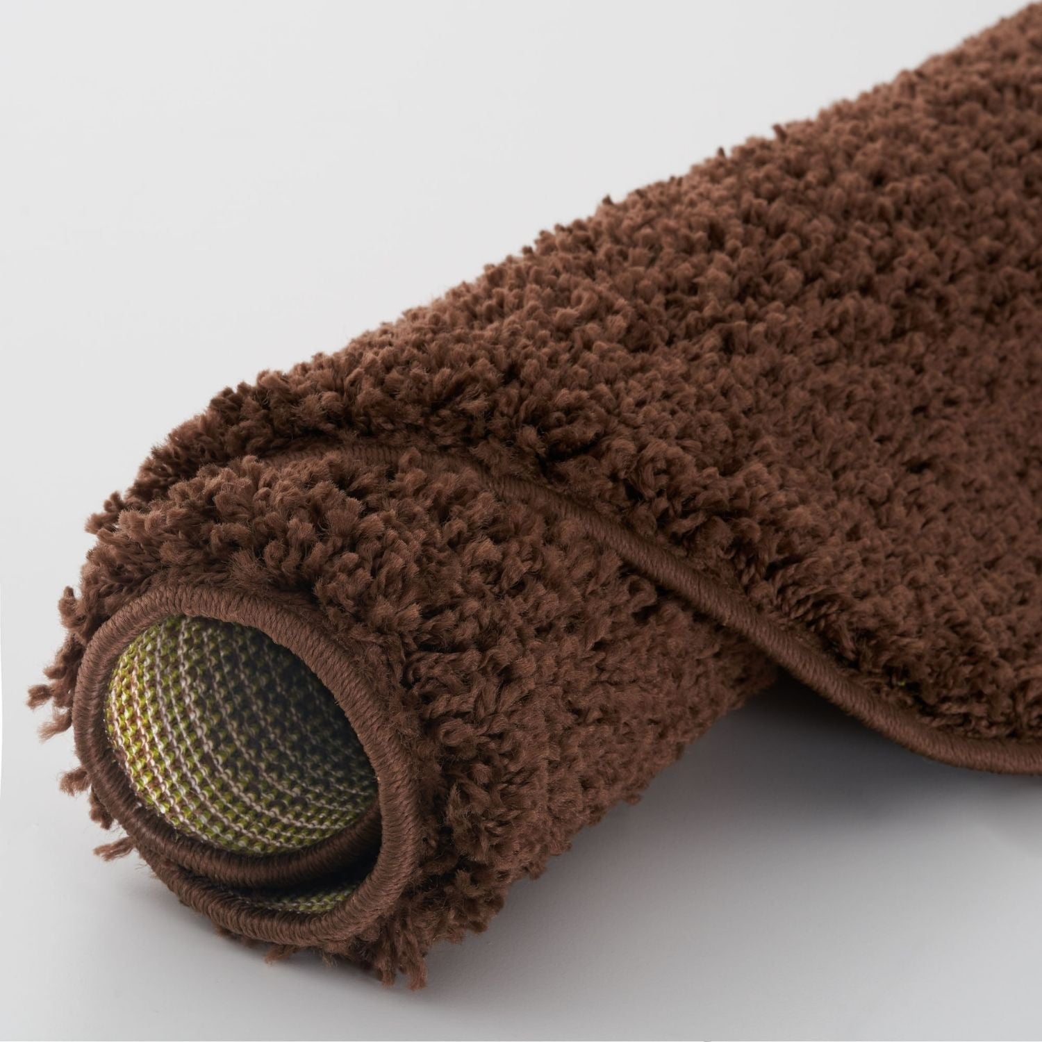 Brown rug roll with plush shaggy texture and yellow green mesh backing from myshaggy solid brown rug collection