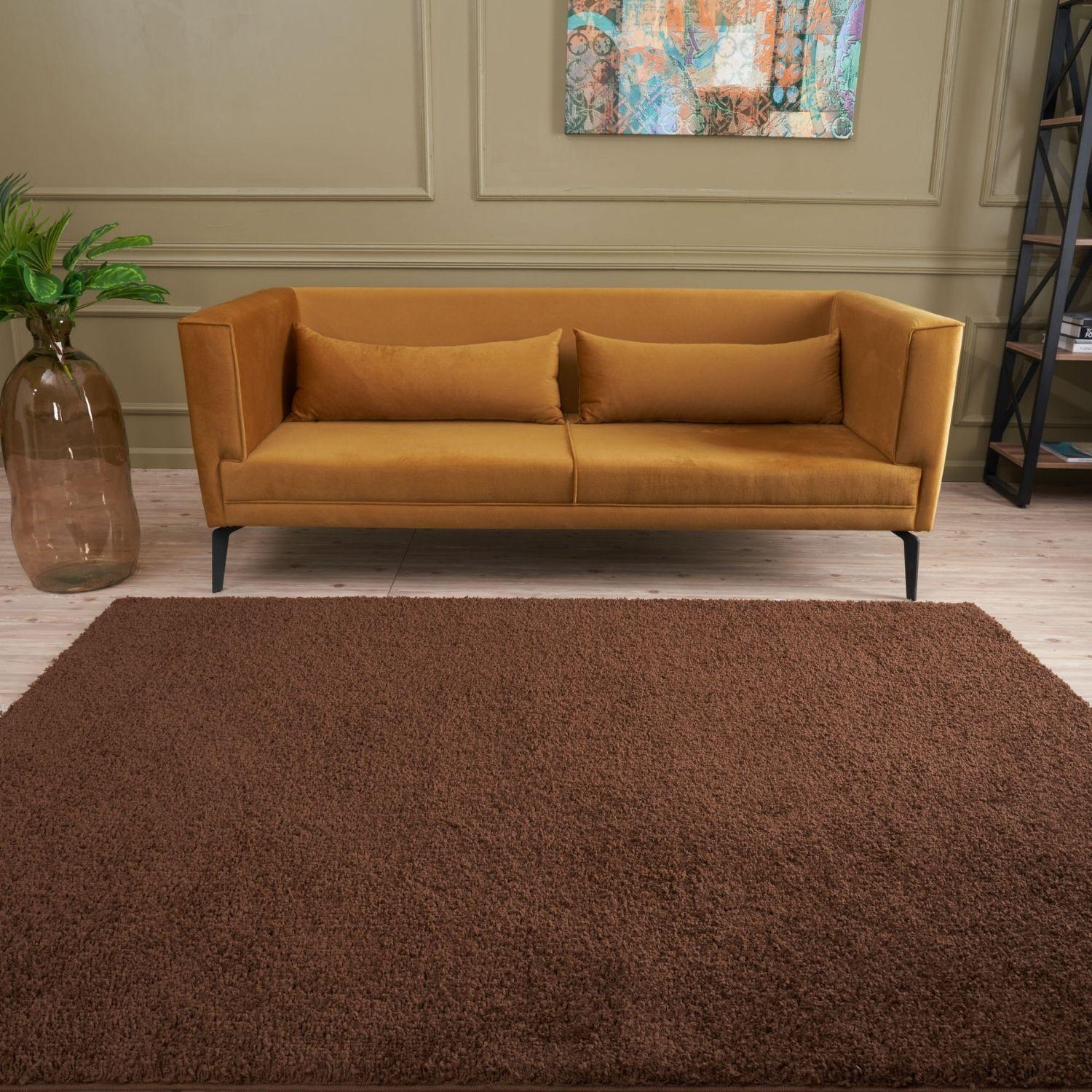 Warm amber velvet sofa with sleek black legs and cushions on a brown rug myshaggy solid brown rug