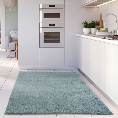A plush duck egg blue shaggy area rug with soft textured surface on white tiled floor perfect for cozy spaces