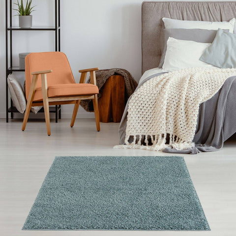 A rectangular teal shaggy rug with plush texture in duck egg blue sits centered in the room foreground