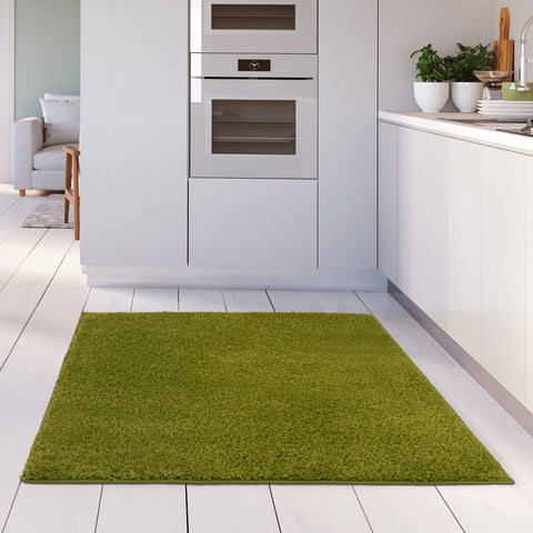 A plush 30mm pile myshaggy solid green rug with a soft shaggy texture on a white wooden floor