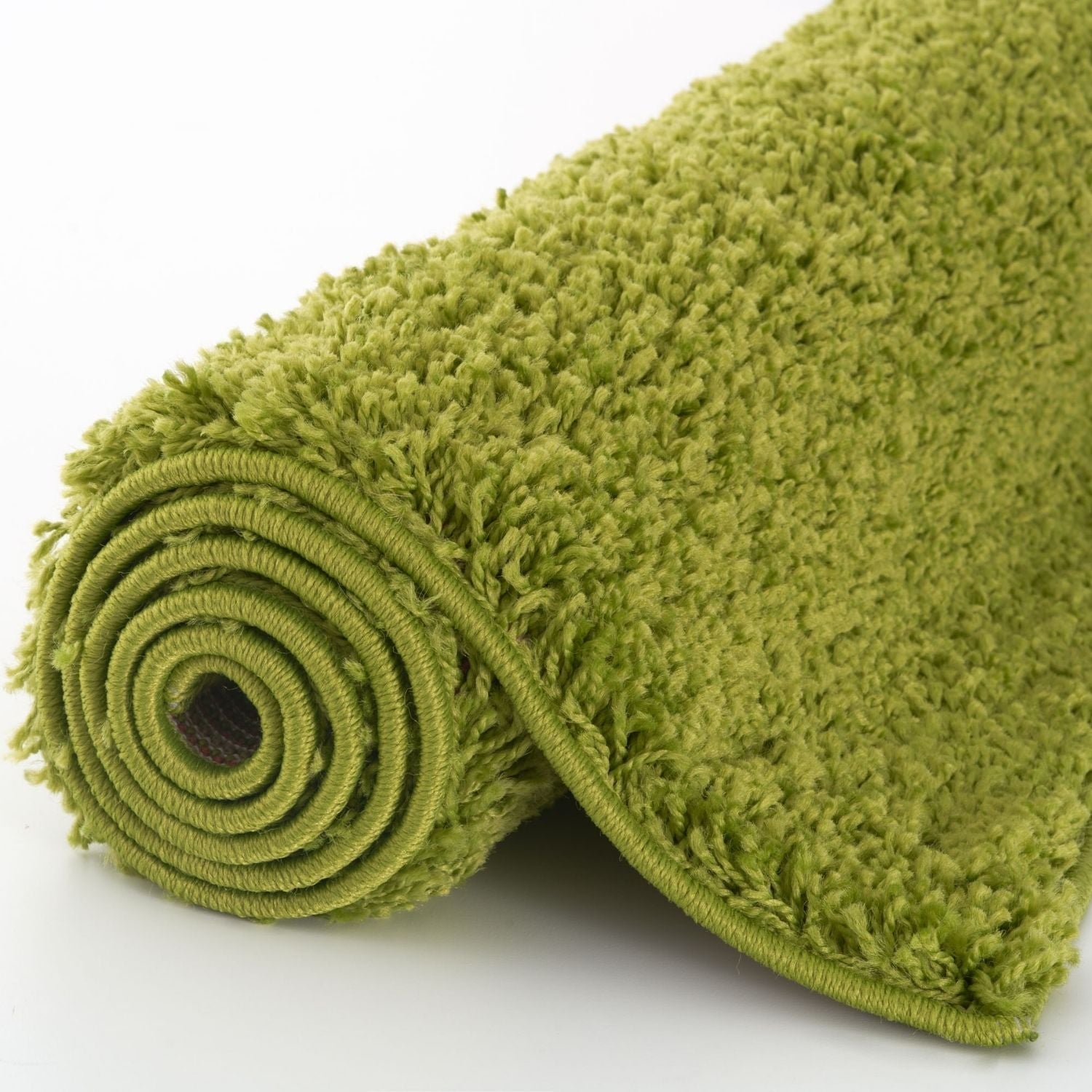 A plush olive green myshaggy solid green rug with 30mm pile rolled neatly on a white surface