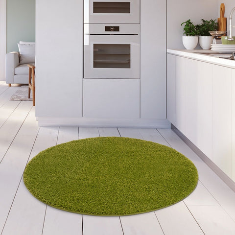 A round plush myshaggy solid green rug with soft shaggy texture and plush 30mm pile on a white wooden floor