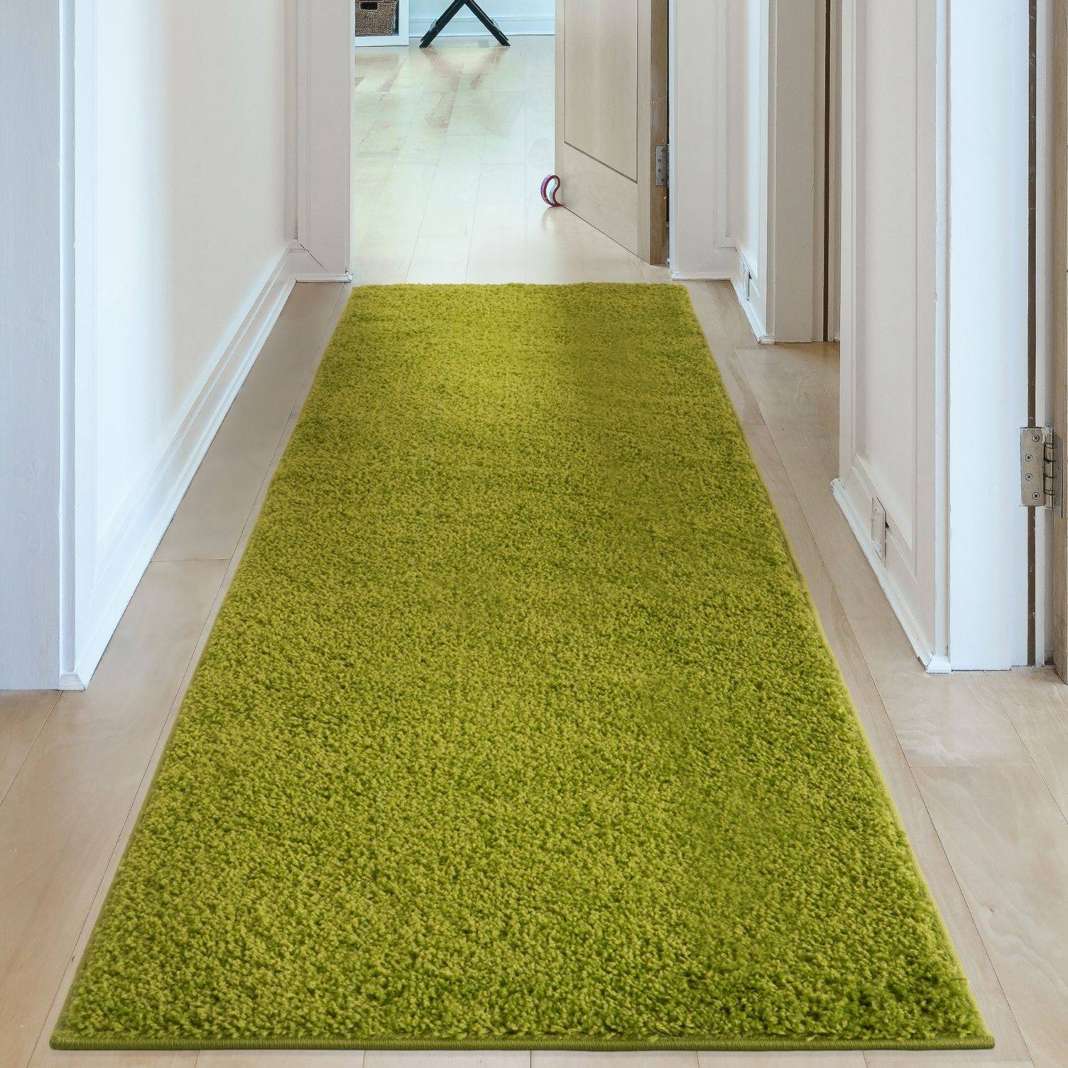 A vibrant lime green myshaggy solid green rug with plush 30mm pile laid on a light wood floor hallway