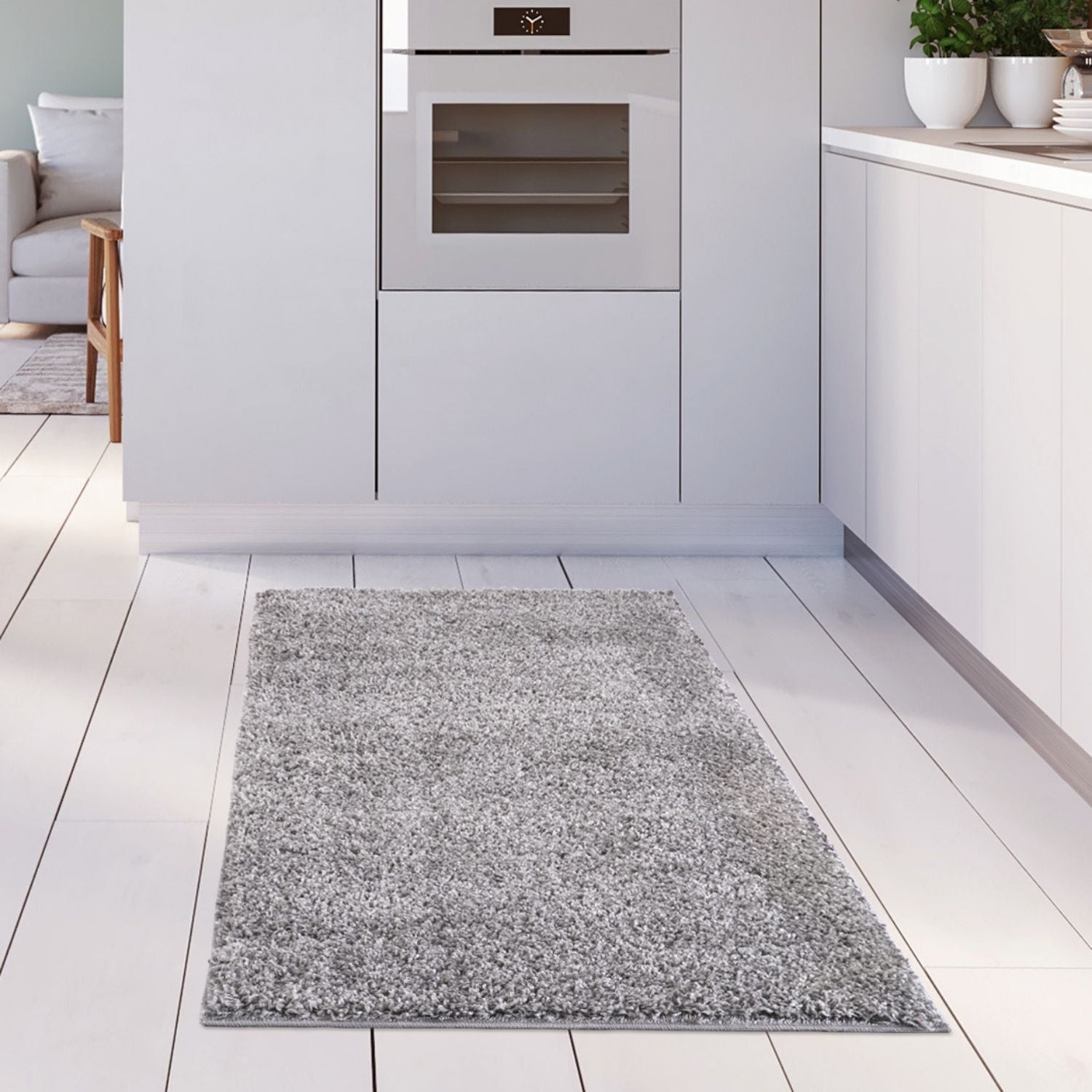 A plush myshaggy solid grey rug with a soft textured surface on a white wooden floor perfect for cozy spaces