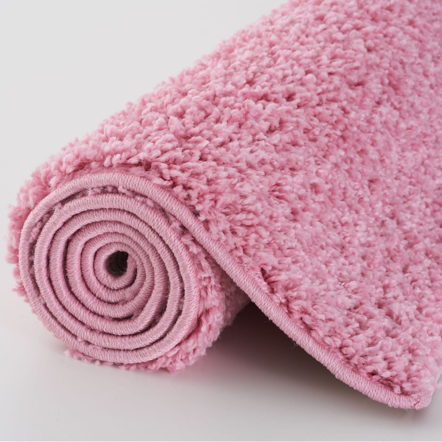 Pink plush bath mat with a soft textured surface and rolled edge from myshaggy solid pink collection solid pink rug