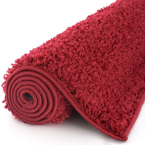 Myshaggy solid red plush shaggy rug rolled neatly on a white surface perfect for cozy home decor