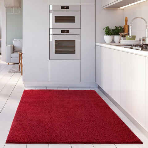 A plush vibrant myshaggy solid red rug with soft shaggy texture on white tiled floor perfect for cozy spaces