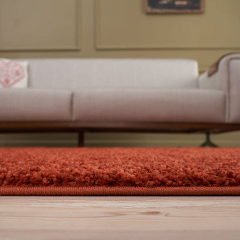 A plush vibrant orange shag rug with dense texture and stitched border from myshaggy solid terra collection