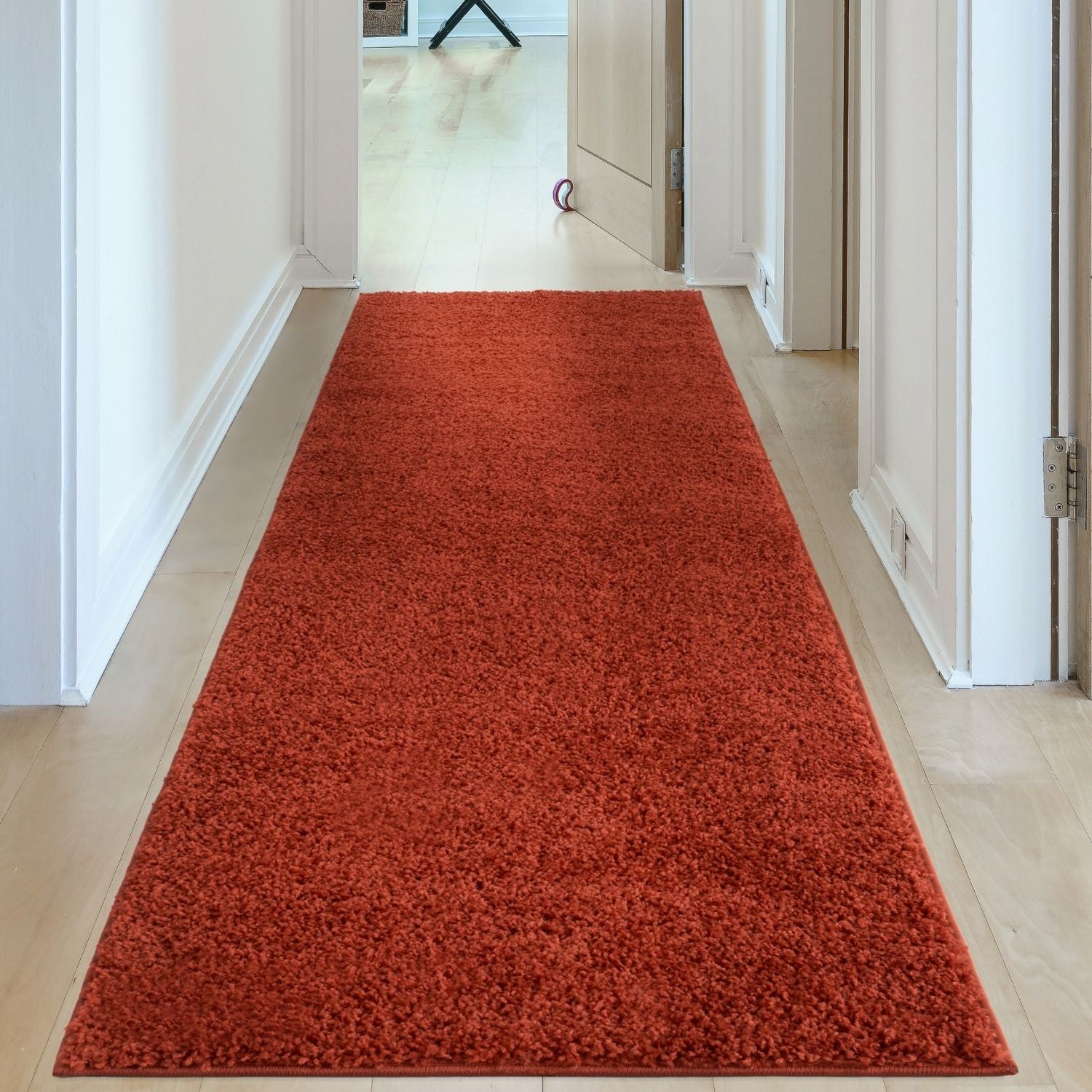 A plush vibrant orange shaggy myshaggy solid terra runner rug laid along a hallway floor for cozy decor