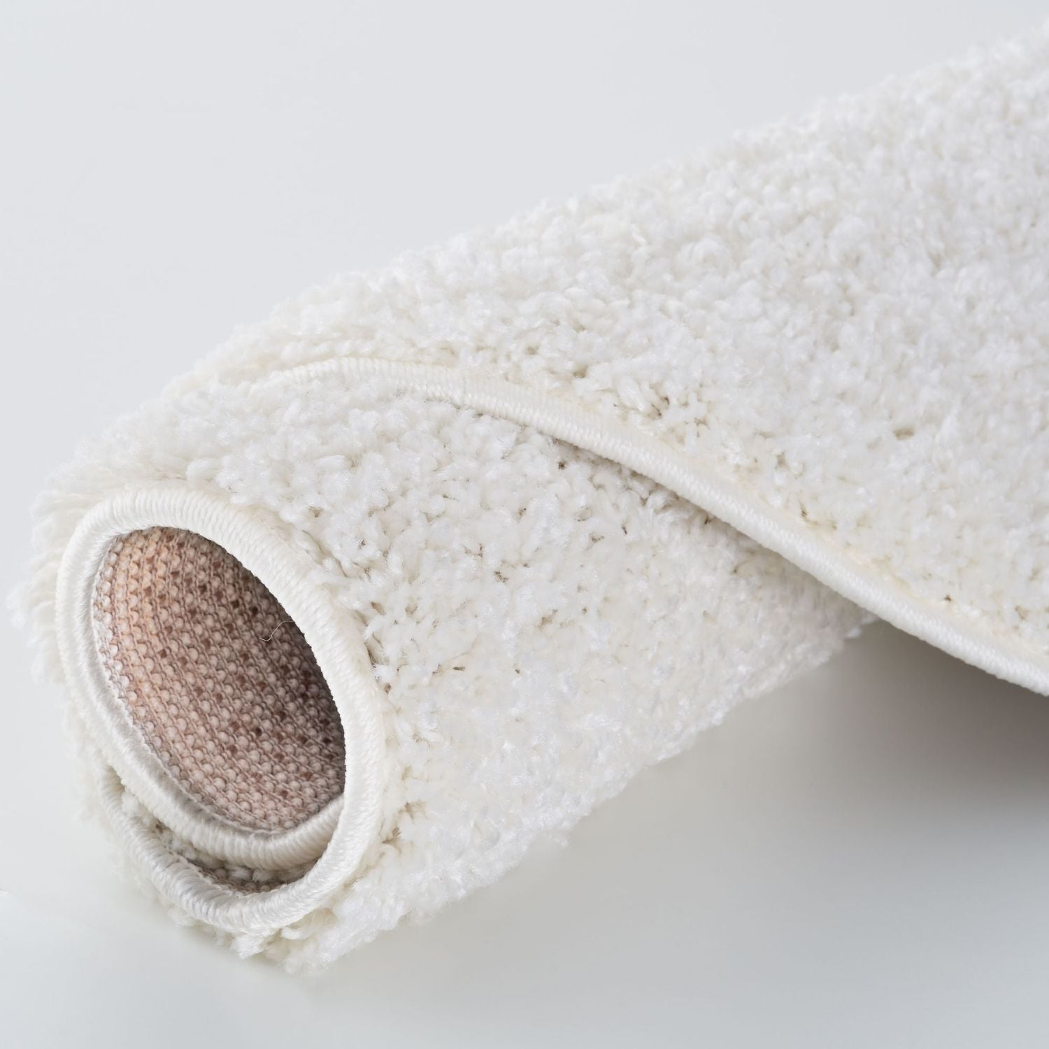 A plush myshaggy solid white bath mat with a soft textured surface and beige woven backing solid white rug