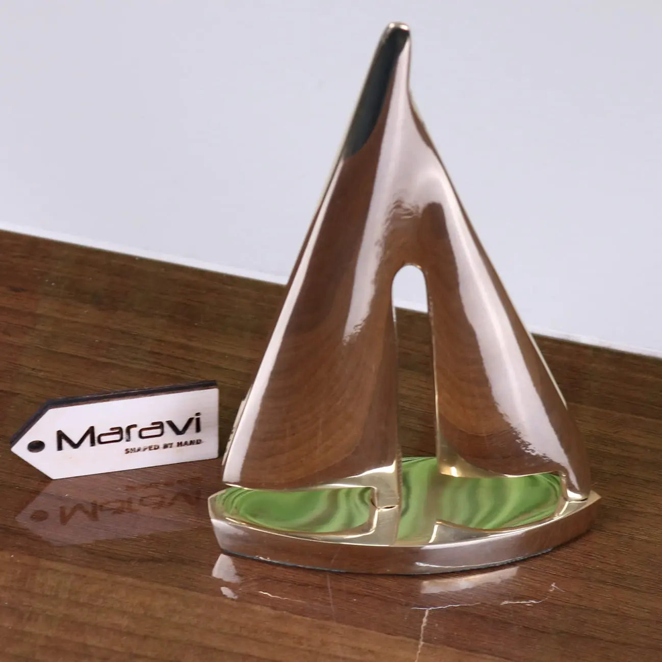 Shiny solid brass yacht model ornament with metallic sailboat and green swirled base branded maravi nabha brass yacht