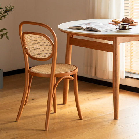 A light wood nadia rattan dining chair with a curved backrest and woven seat perfect as a rattan dining chair