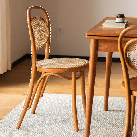 A light brown nadia rattan dining chair with a cane back, woven seat, and curved wooden legs perfect for dining rooms