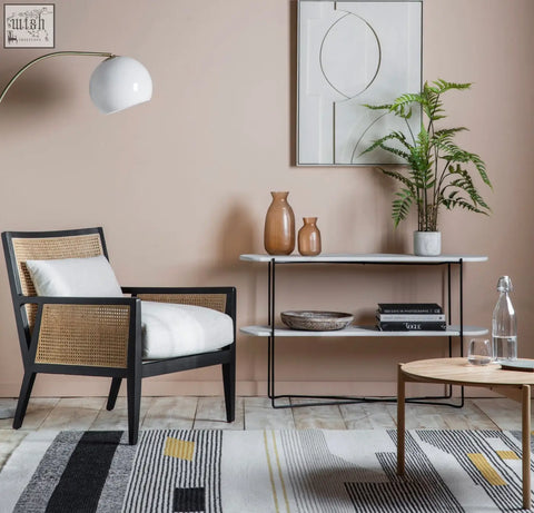 Black-framed nagoya rattan armchair with woven cane back and seat and white cushions in natural black finish