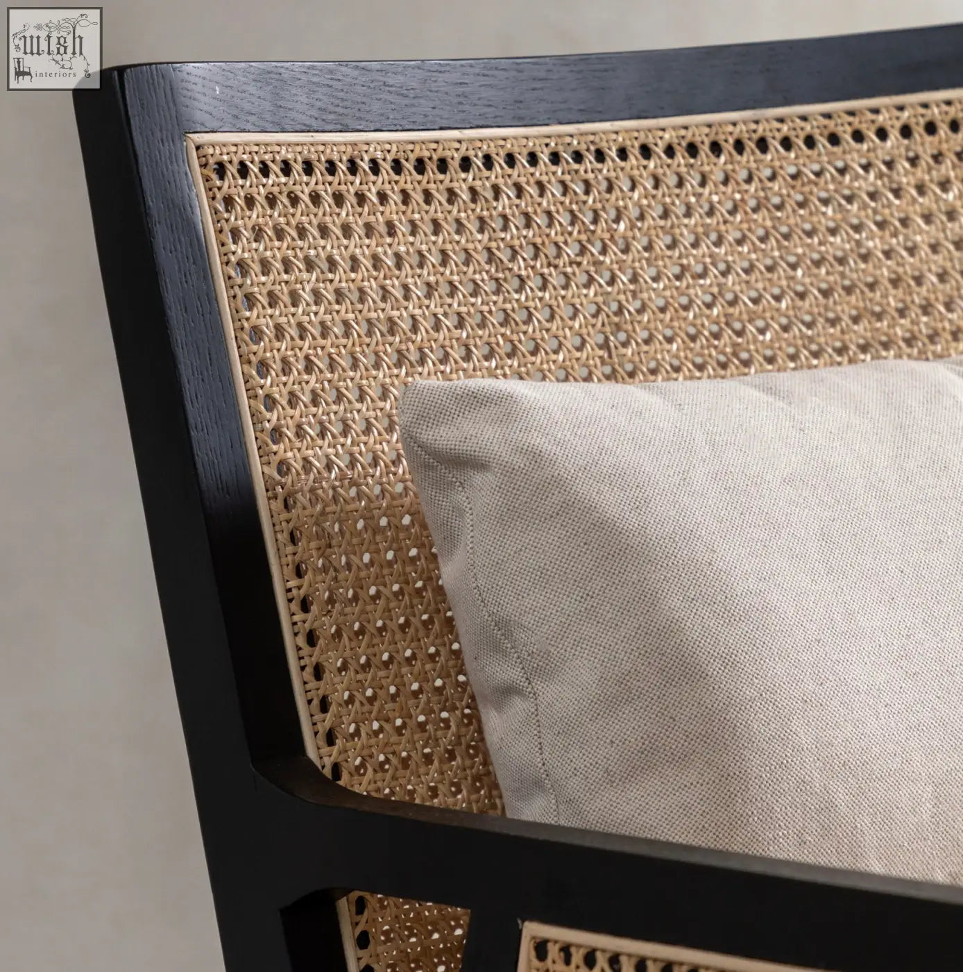 Nagoya rattan arm chair with black frame and light beige cushion featuring a stylish cane design