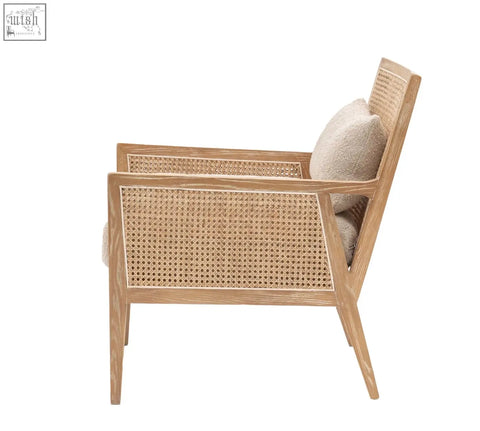 A nagoya rattan arm chair with light wood frame, woven cane back and seat, and a soft beige cushion in natural black