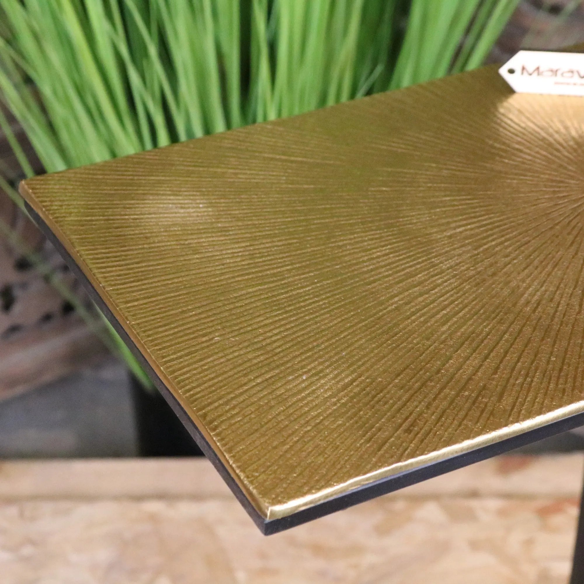 Nalora gold sofa table with a gold-colored square top featuring sunburst texture and black edges perfect for a gold sofa setup