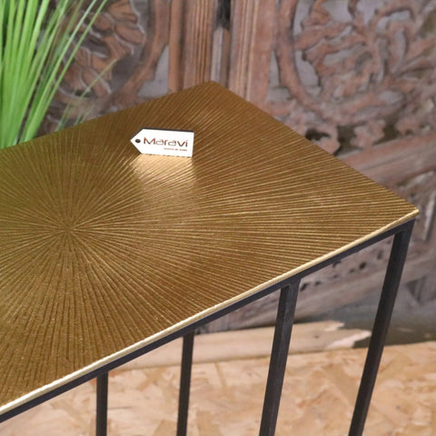 Gold sofa table with gold-finished metal sunburst textured top and black wrought iron legs called nalora gold sofa table