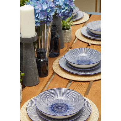Blue and white ceramic bowl with circular patterns on teak wood dining table in natural slatted wood dining setting