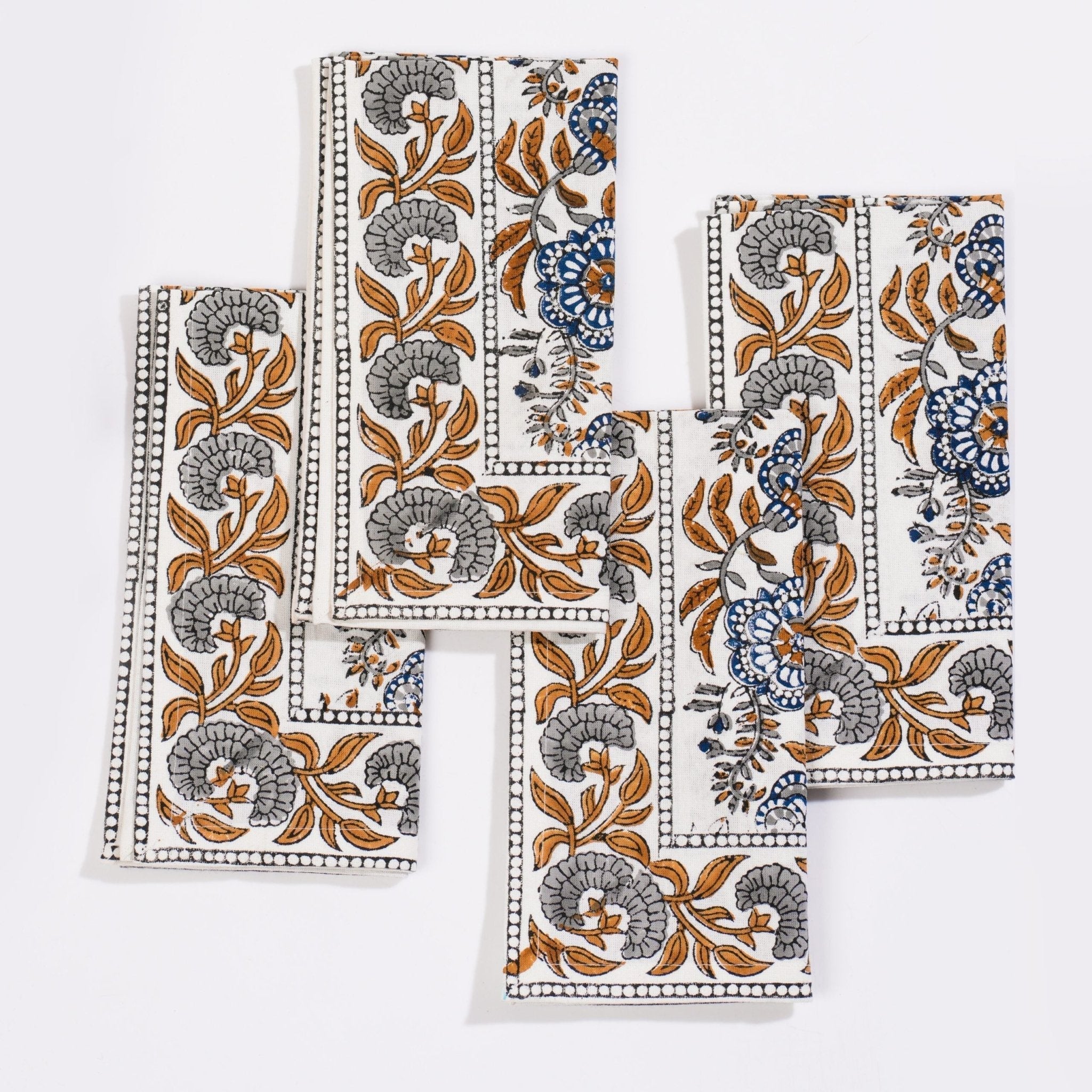 Set of four white cotton napkins with blue and gray floral patterns and dotted border from coromandel nut blue collection