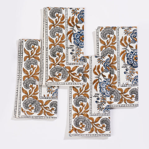 Set of four white cotton napkins with blue and gray floral patterns and dotted border from coromandel nut blue collection