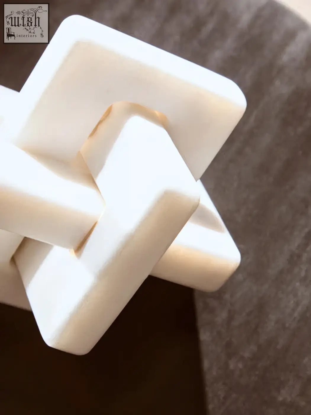 White plastic geometric puzzle piece resembling a white marble knot sculpture with interlocking square shapes