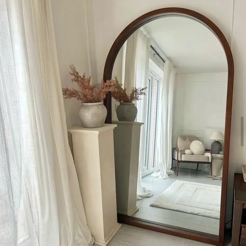 A tall arched natsuki mirror with a dark wood frame perfect for adding elegance to any room