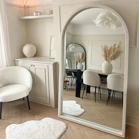 Natsuki mirror is a tall arched white framed mirror reflecting an elegant room decor with a sleek design