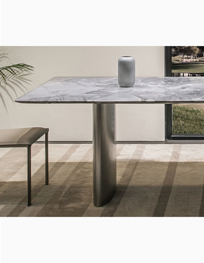 A sleek gray vase with matte finish on a natural marble dining table with a polished marble tabletop surface