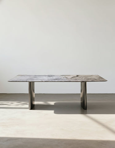 A sleek rectangular natural marble dining table with gray marble top and polished chrome legs perfect for dining rooms