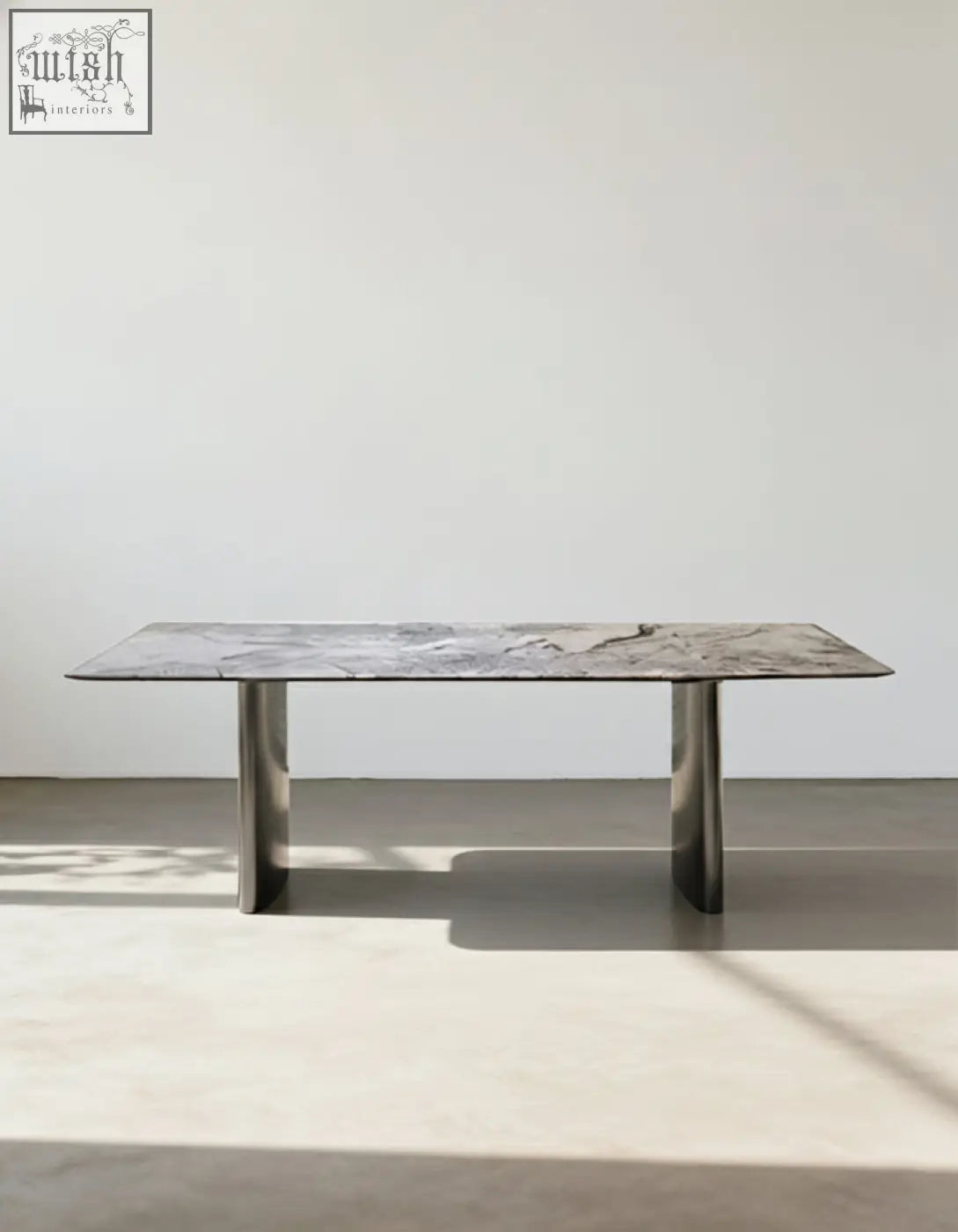 A sleek natural marble dining table with a gray marble top and polished chrome legs that adds modern style