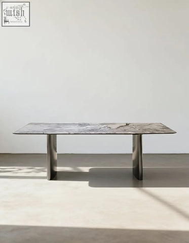 A sleek natural marble dining table with a gray marble top and polished chrome legs that adds modern style