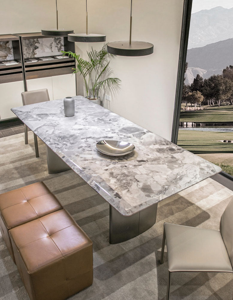 A sleek rectangular dining table with a polished gray and white natural marble top and modern metallic legs