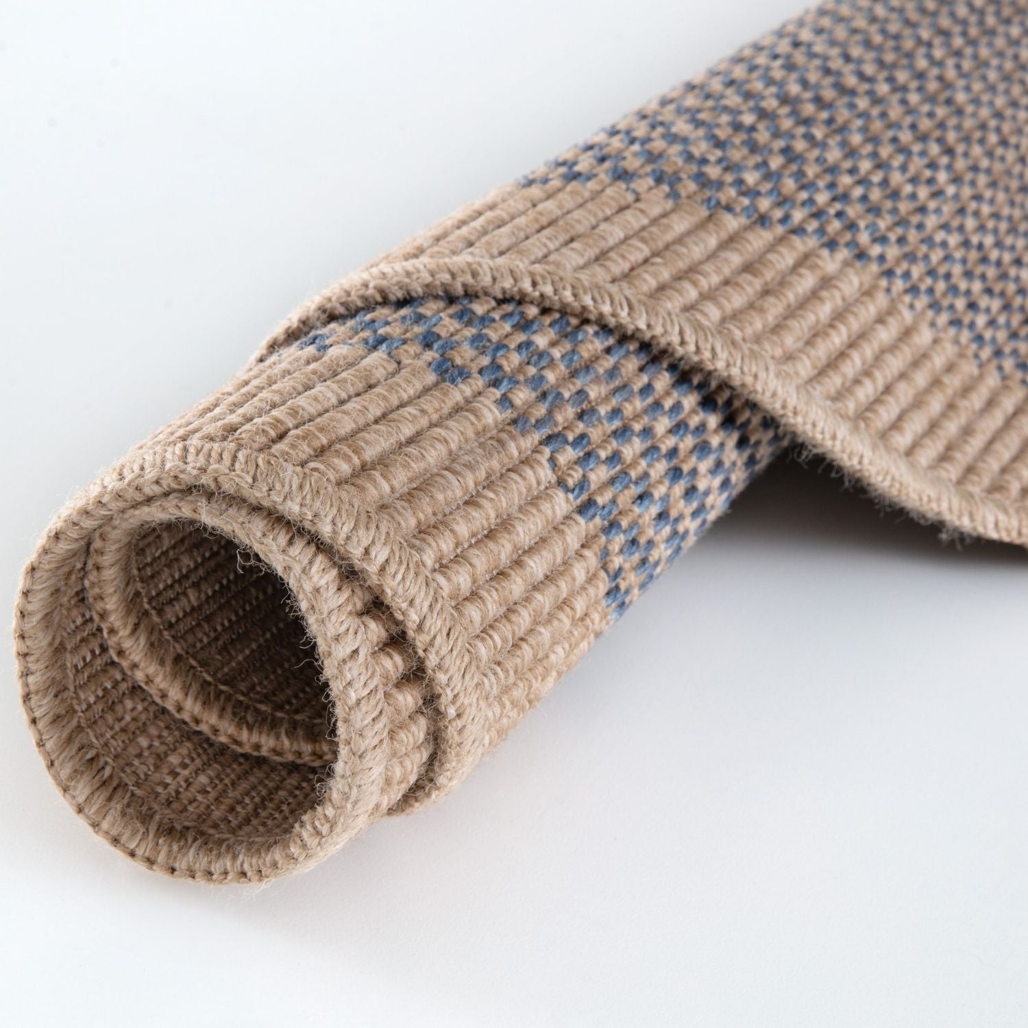 Rolled beige and blue woven nature outdoor rug with textured natural fiber weave perfect for outdoor use